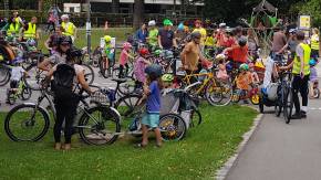 In einem Park versammelt sich eine große Gruppe vornehmlich junger Menschen mit Fahrrädern, darunter auch viele Kinder.